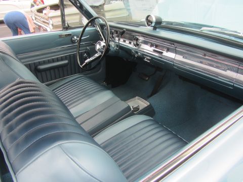 1964 Ford Ranchero - The interior of a 1964 Ford Ranchero features blue vinyl seats and a matching dashboard with chrome accents.