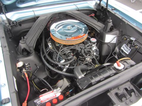1964 Ford Ranchero - The engine bay of a classic Ford Falcon, a 289 cubic inch V8 engine with a prominent chrome air filter housing.