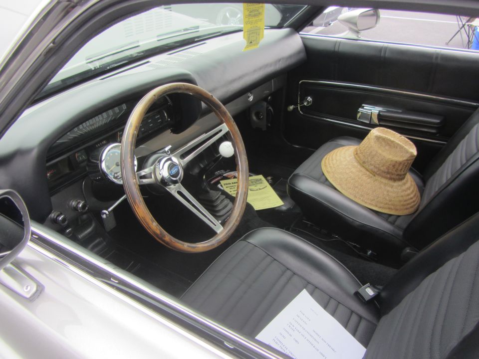 Interior of a 1964 Ford Ranchero with a wooden steering wheel and straw hat on the seat