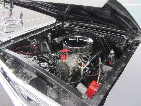 1964 Ford Ranchero - The engine bay of a 1964 Ford Ranchero is open, revealing its V8 engine and various components.