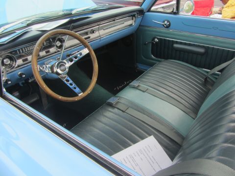 1964 Ford Ranchero - The interior of a light blue 1964 Ford Ranchero shows a wooden steering wheel and a two-tone bench seat.