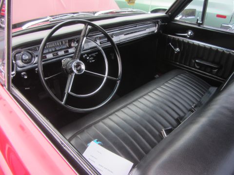 1964 Ford Ranchero - Interior view of a red 1964 Ford Ranchero, showing the dashboard, steering wheel, and bench seat.