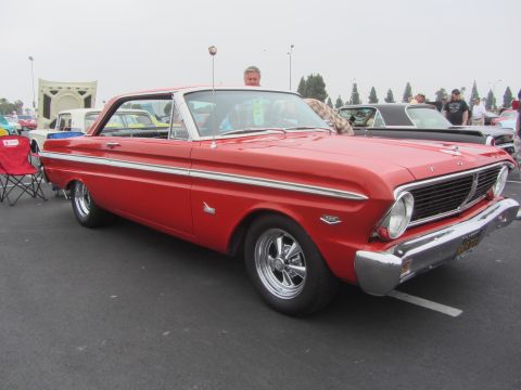 1964 Ford Ranchero - A red 1963 Ford Falcon Futura is parked at an outdoor event, showing off its classic lines and chrome details.