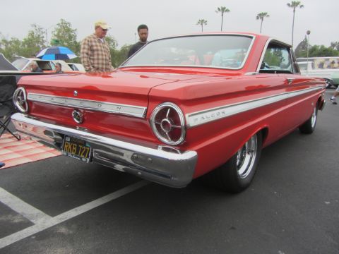 1964 Ford Ranchero - A red classic car is parked outdoors, showing its rear end and side profile with chrome accents.