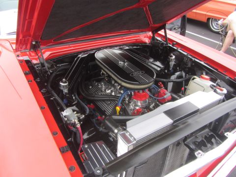 1964 Ford Ranchero - The engine bay of a red 1964 Ford Ranchero, a V8 engine with a prominent Ford air cleaner and chrome accents.