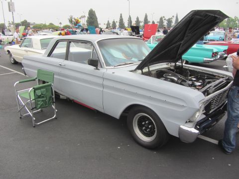 1964 Ford Ranchero - A light gray 1964 Ford Ranchero is parked with its hood open, showing the engine and black racing wheels.