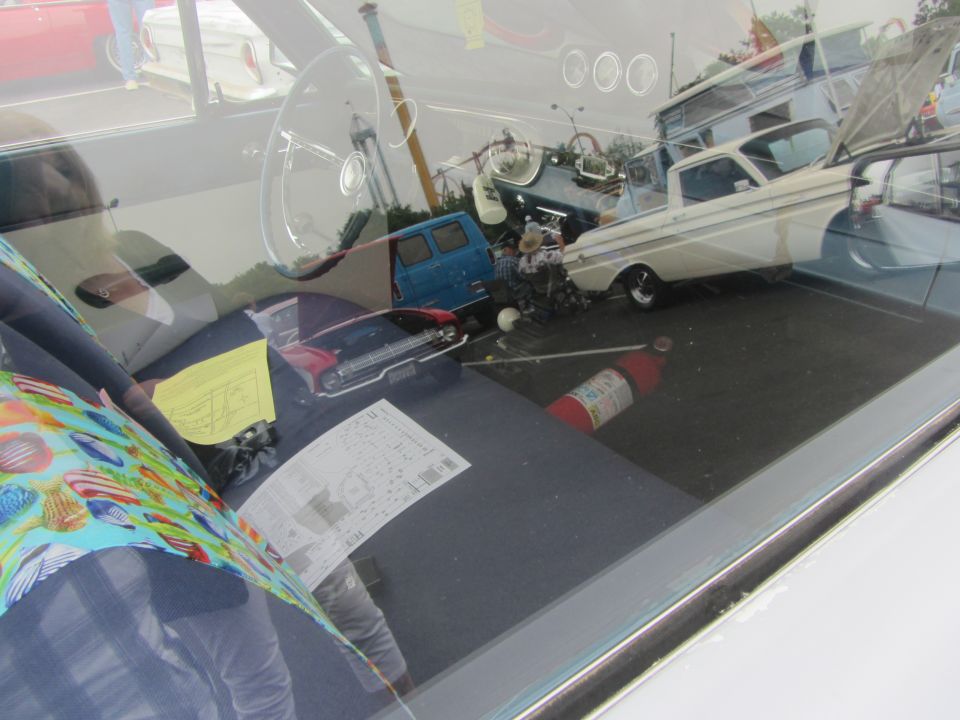 1964 Ford Ranchero interior showing steering wheel, fire extinguisher, and reflections of other vehicles outside