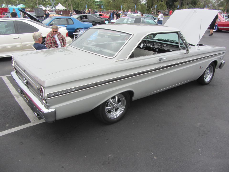 Silver 1964 Ford Falcon coupe, hood open, parked in lot with other cars