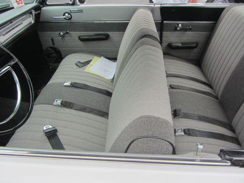 1964 Ford Ranchero - The interior of a classic car shows a bench seat with seatbelts and a piece of paper on the passenger side.