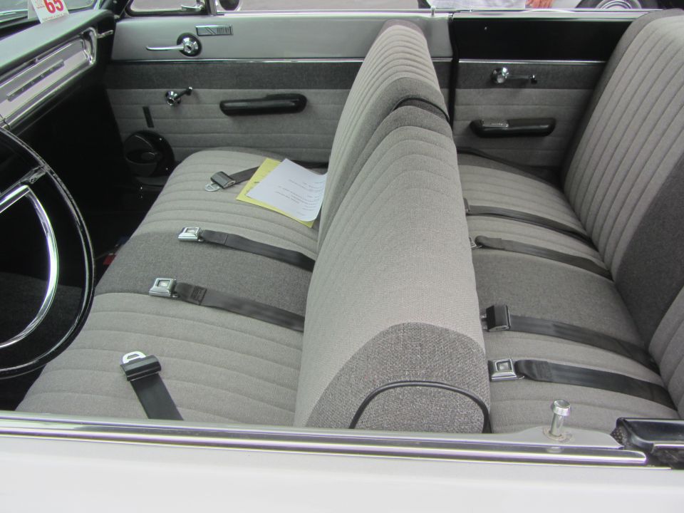 Car interior with bench seat, seatbelts, and a paper on the seat