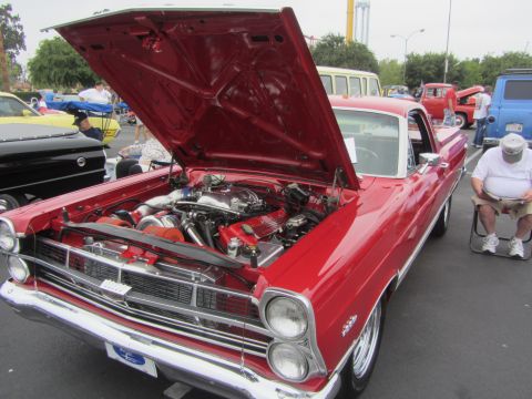 1964 Ford Ranchero - A red 1965 pickup truck is displayed with its hood open, revealing a powerful engine setup with twin turbos.