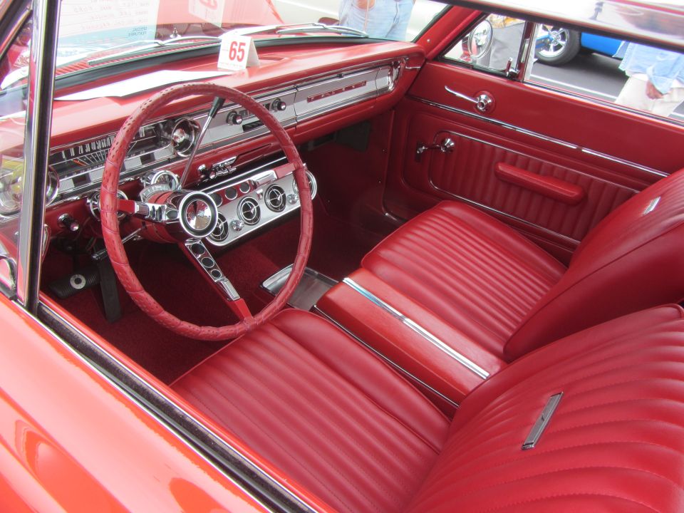 red car interior with bench seats, steering wheel, and dashboard
