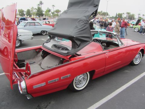 1964 Ford Ranchero - A red convertible with its trunk and soft top open, parked at an outdoor car show.