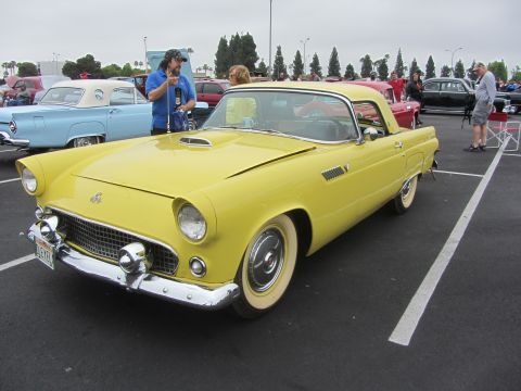 1964 Ford Ranchero - A yellow 1955 Ford Thunderbird convertible is parked at an outdoor car show with other vehicles visible.