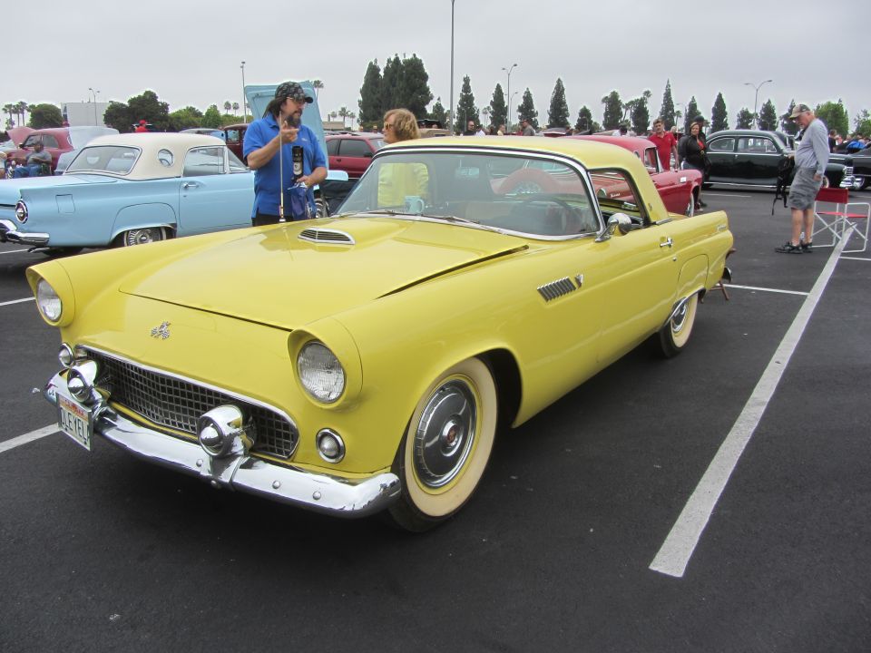 Yellow 1955 Ford Thunderbird convertible with a white hardtop, chrome grille, and whitewall tires