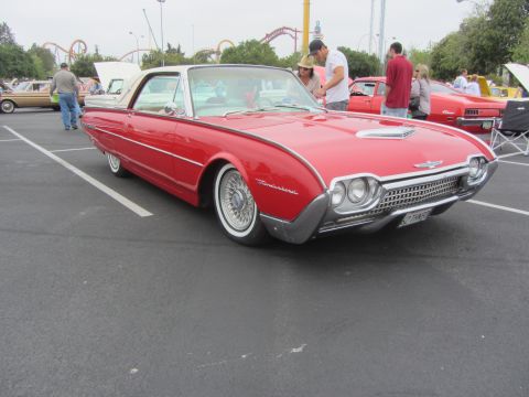 1964 Ford Ranchero - A red 1961 Ford Thunderbird is parked in a lot, with other vehicles and people around.