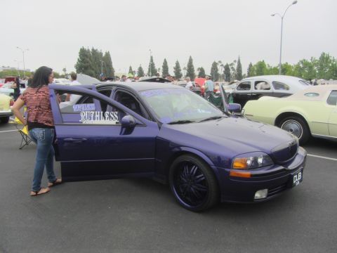 1964 Ford Ranchero - A purple sedan with custom rims and doors open is parked at an outdoor event with other vehicles.