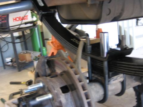 1995 Ford Bronco - New rear leaf springs are installed on a vehicle's axle, with a brake rotor and hub assembly in the foreground.