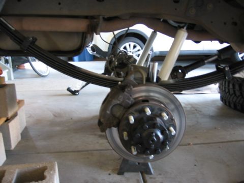 1995 Ford Bronco - The rear suspension and brake system of a vehicle are shown while undergoing maintenance.