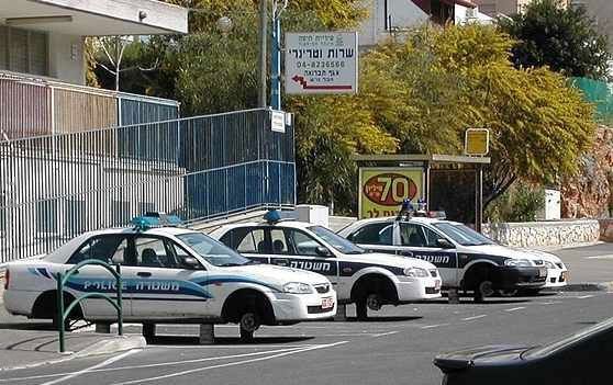 Three white police cars parked outside with Hebrew and English Police markings