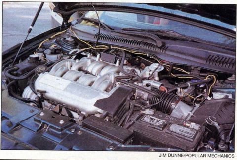 1997 Ford Taurus - Scanned magazine photo of a transverse V8 engine bay, showing a cast aluminum intake manifold with long curved runners and a Ford oval badg…