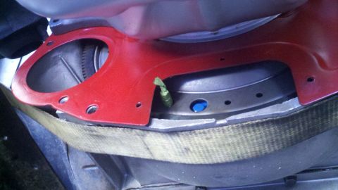 1978 Ford Bronco - Close-up view of a red engine component with visible metal bracing and a yellow strap, likely during a repair or rebuild process.