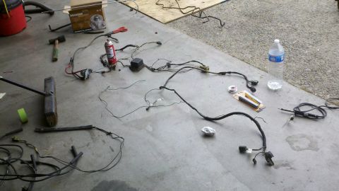 1978 Ford Bronco - A disassembled vehicle wiring harness is spread out on the floor, surrounded by tools and supplies.