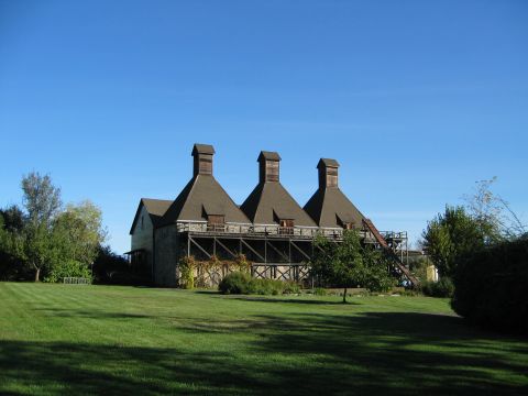 2002 Ford Taurus - A historic building with three distinctive chimneys stands under a clear blue sky, surrounded by green grass and trees.