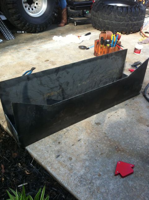 1989 Ford Bronco - Metal parts are laid out on a concrete surface, with tools and large tires visible in the background.