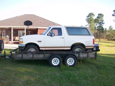 1995 Ford Bronco - A white 1995 Ford Bronco is transported on a trailer, seen from the side.