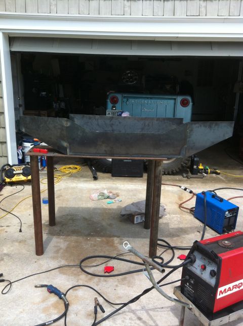 1989 Ford Bronco - A custom metal bumper is being fabricated in a garage, with welding equipment nearby and a vintage International Scout visible.