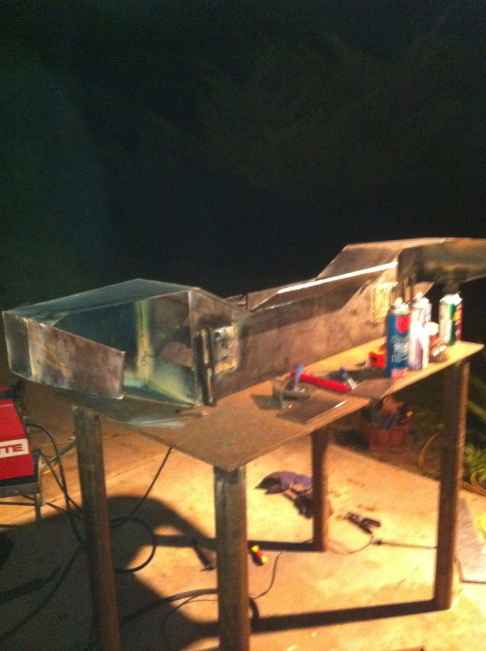 Custom metal fabrication project on a workbench with tools and cans