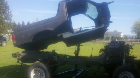 1988 Ford Bronco - The body of a 1988 Ford Bronco is lifted off its chassis, revealing the engine and frame.