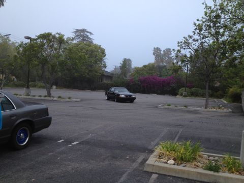 2004 Ford Crown Victoria - A black sedan with a distinctive fox body style navigates a foggy parking lot.