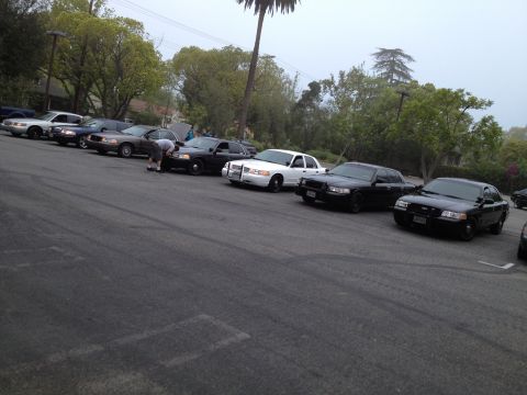 2004 Ford Crown Victoria - A group of Ford Crown Victoria police sedans are parked together in a lot.