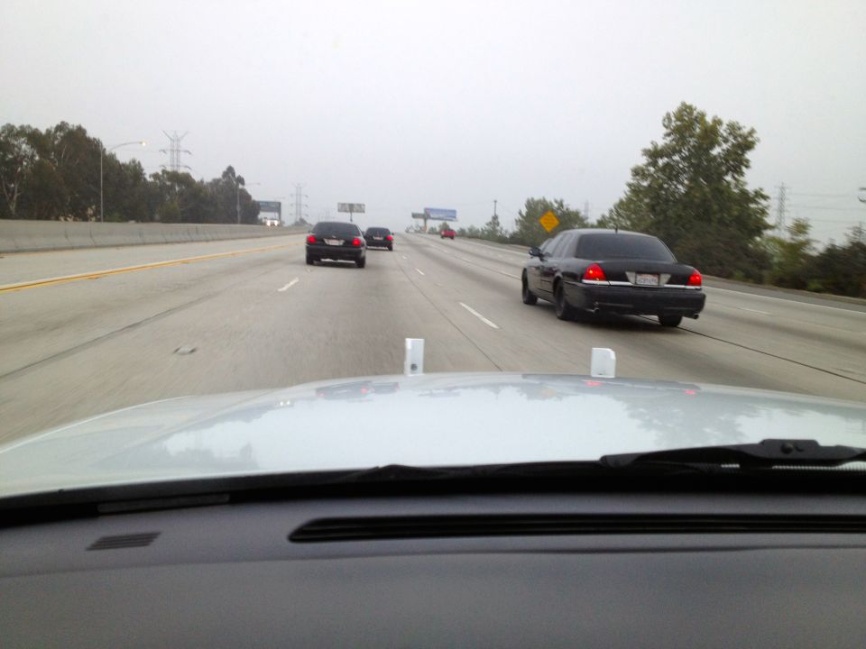 Black sedan driving on a foggy highway, other cars ahead