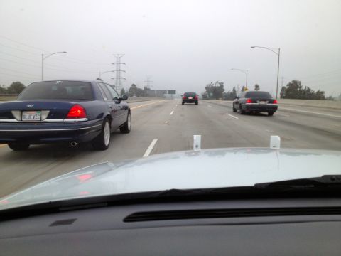 2004 Ford Crown Victoria - A blue Ford Crown Victoria drives on the highway alongside other vehicles.