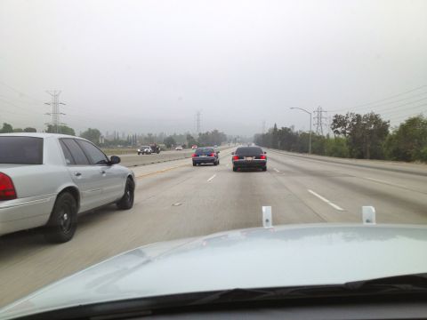 2004 Ford Crown Victoria - A silver 2004 Ford Crown Victoria is seen on a highway, traveling alongside other vehicles under foggy conditions.