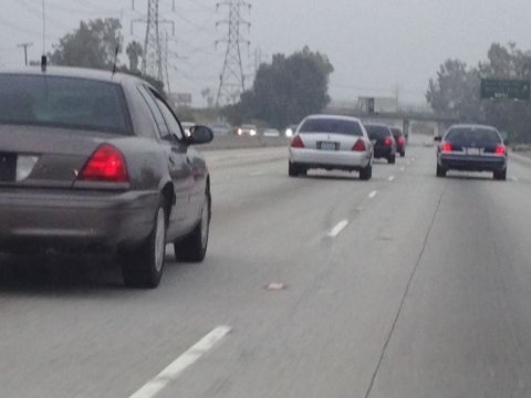 2004 Ford Crown Victoria - Multiple Ford Crown Victorias drive on a highway under an overcast sky.