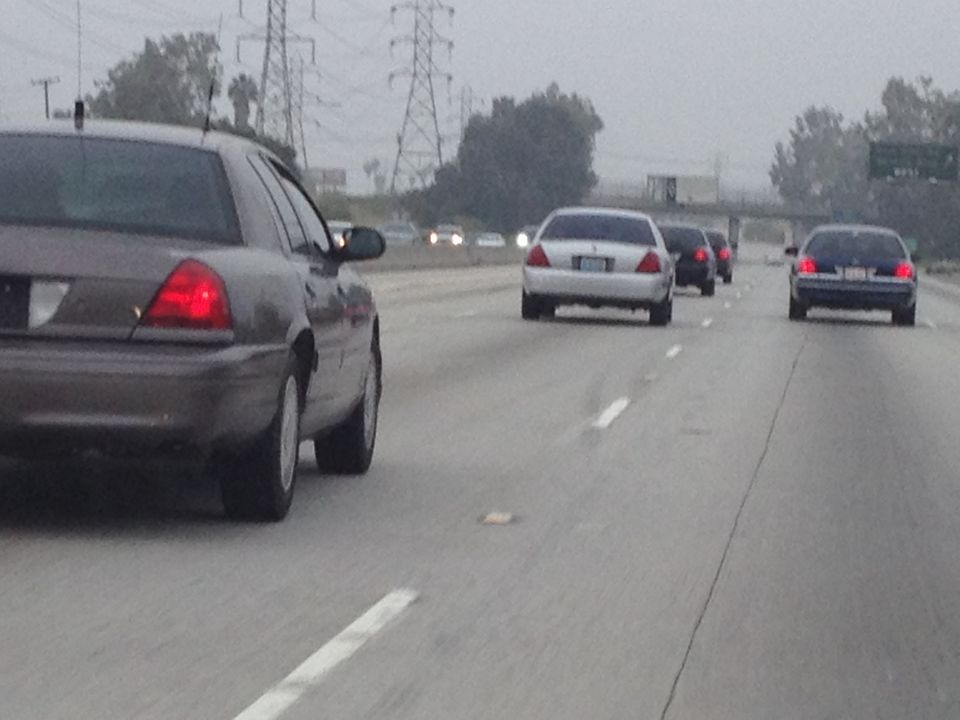 Dark gray Ford Crown Victoria rear view on highway, showing taillights and rear bumper