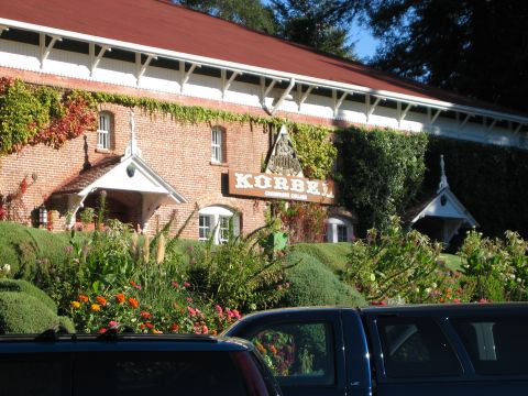 2002 Ford Taurus - Ivy-covered brick winery building with a red roof and a large "Korbel Champagne Cellars" sign, fronted by flower beds and clipped hedges. T…
