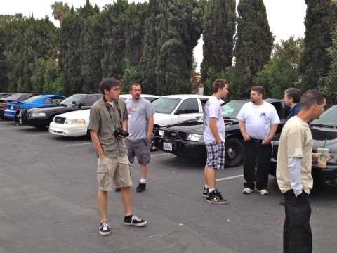 2004 Ford Crown Victoria - Several people stand around a line of parked Ford Crown Victoria sedans.