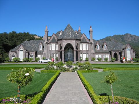 2002 Ford Taurus - A grand stone mansion is set against a clear blue sky, with lush green lawns and formal gardens.