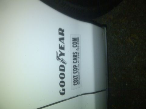 2000 Ford Crown Victoria - Vehicle door shows Goodyear and Colt Cop Cars stickers, with contact information.