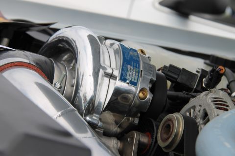 2004 Ford Crown Victoria - Close-up of a polished supercharger with a blue label, part of a vehicle's engine.