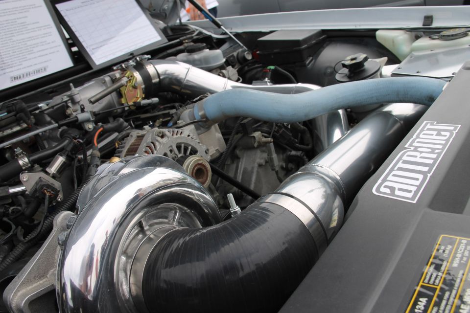 Engine bay with large chrome turbocharger, intercooler piping, and an "ADTR.NET" sticker