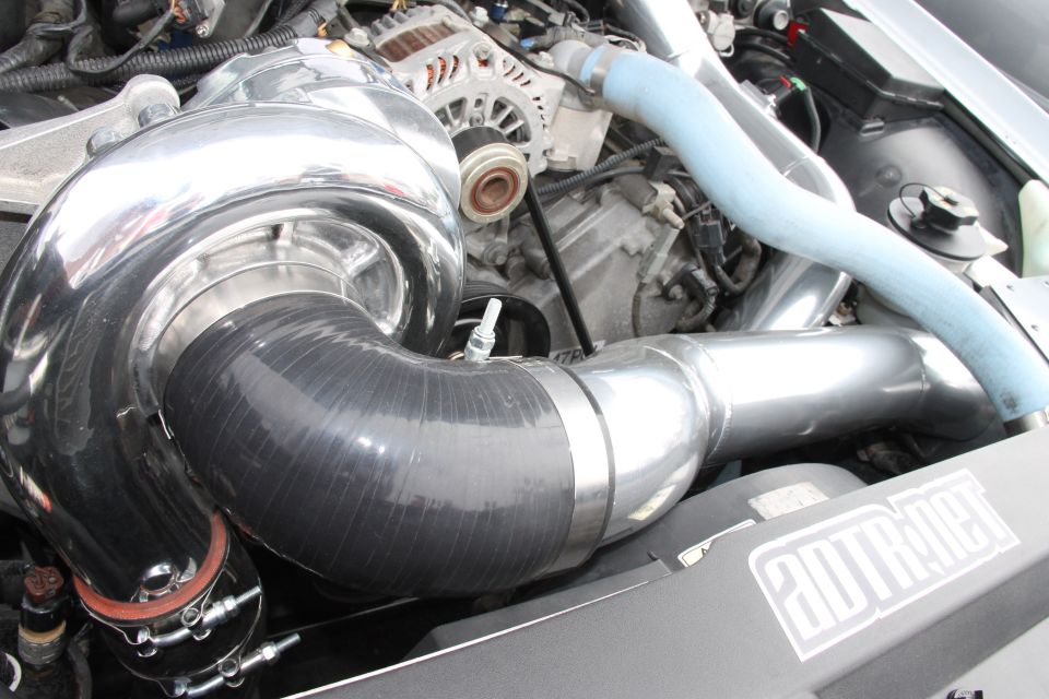 engine bay with large chrome turbocharger and blue intercooler piping