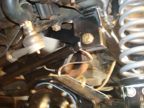 1995 Ford Bronco - Undercarriage view of steering linkage and suspension components, including a coil spring and differential housing.