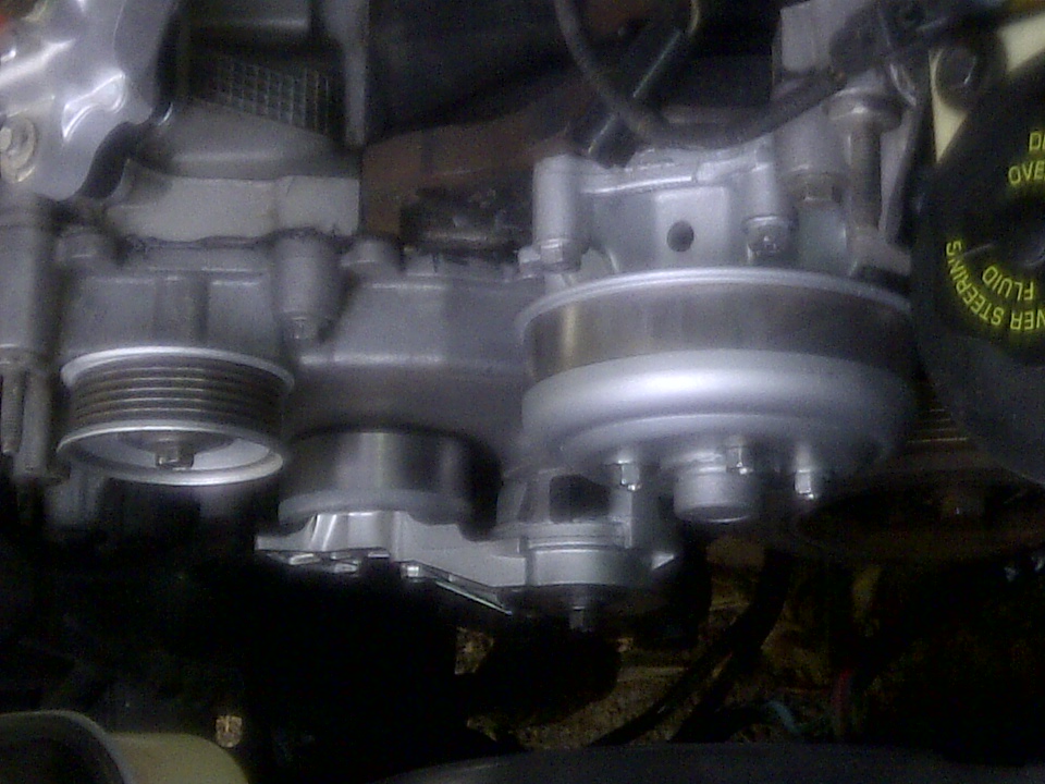 Engine pulleys and belts, with a black cap labeled 'POWER STEERING FLUID'