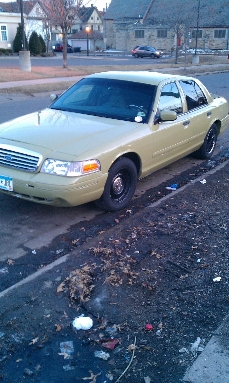 Tan 2000 Ford Crown Victoria, 3/4 front view, parked on a dirty curb
